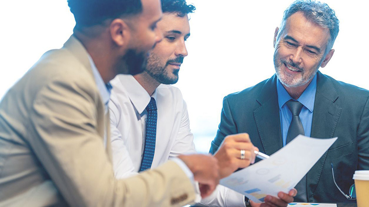 three businessmen examining paper