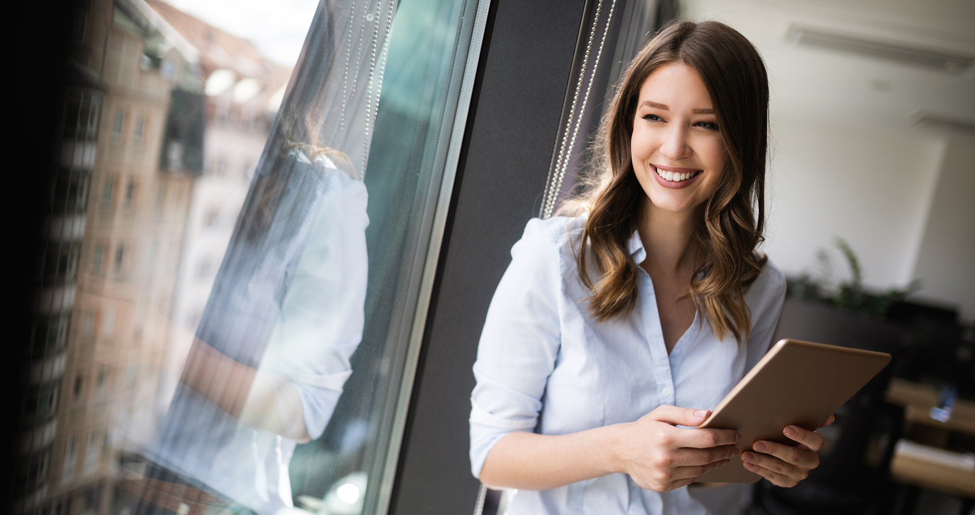 a woman holding a tablet and smiling 