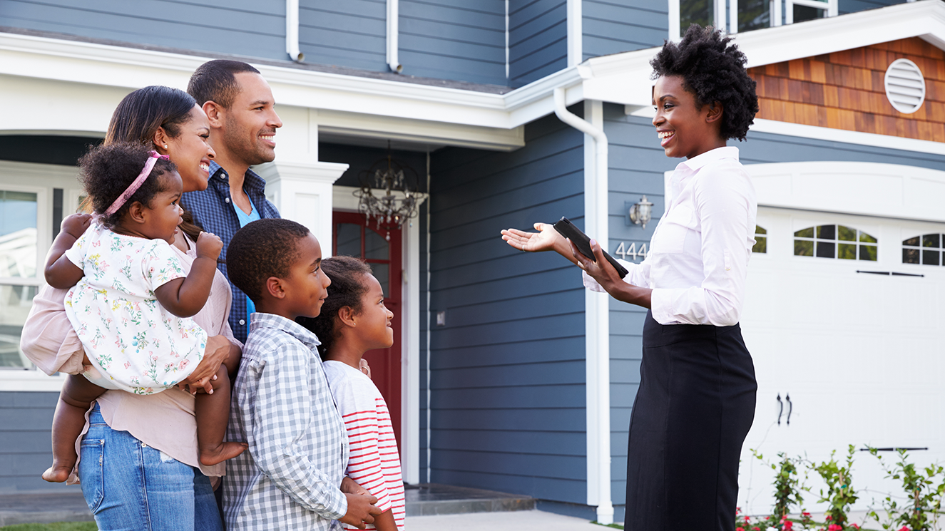 Photo of a realtor showing a family a house.