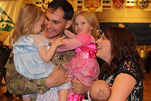 a military member greeting his wife and children after a deployment