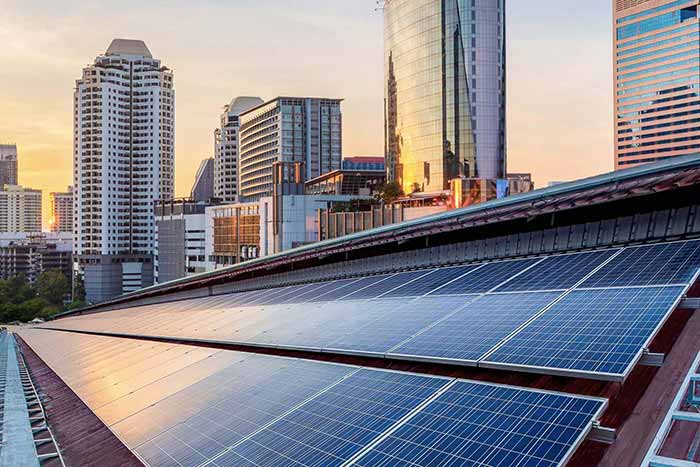 Aerial photo of a large swath of solar panels on top of a building in a downtown area.