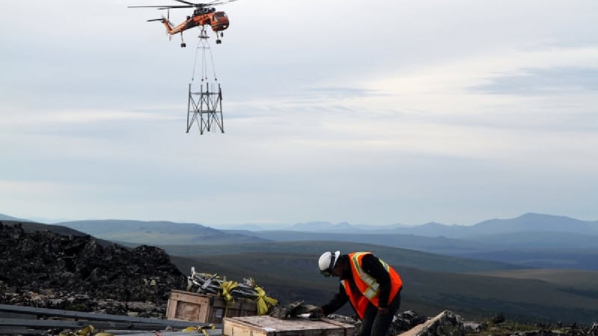 Man working while helicopter lowers item.