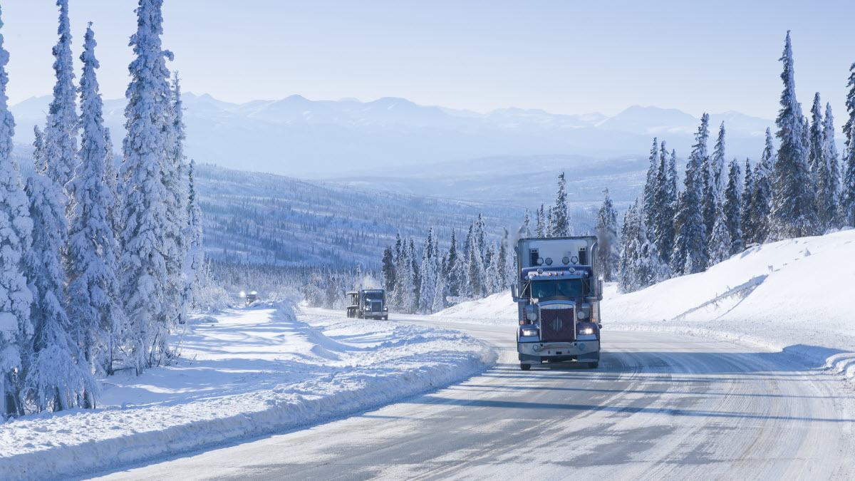 Semi-truck driving past blooming trees. 