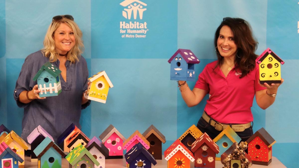 Women holding colorful birdhouses