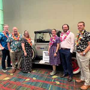 People in Hawaiian attire standing by car