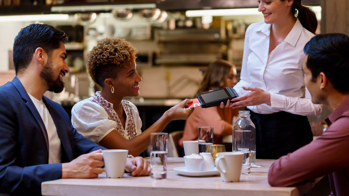 People dining in a restaurant, paying with a credit card