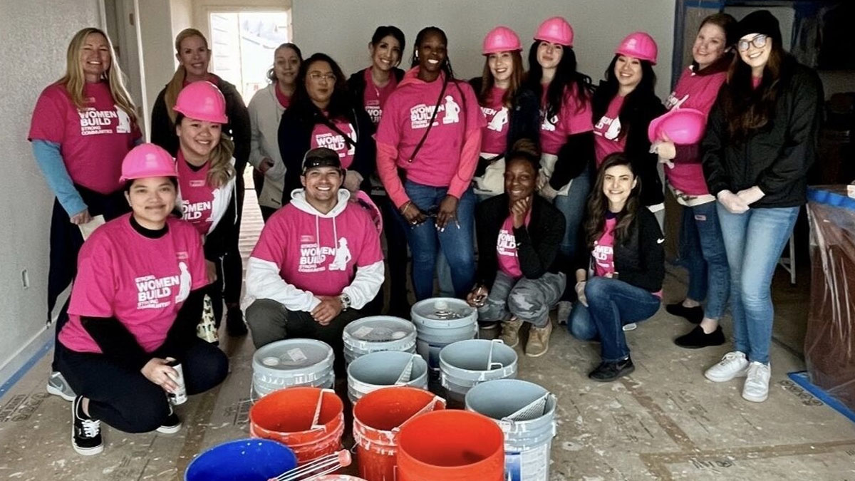 Large group of women, and one man, at a construction site.