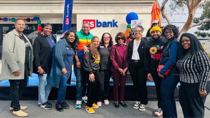 A group of U.S. Bank employees and community members standing in front of a bank branch.