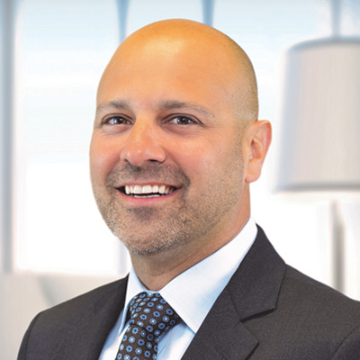 Headshot of Brian Bekiers wearing a suit and tie