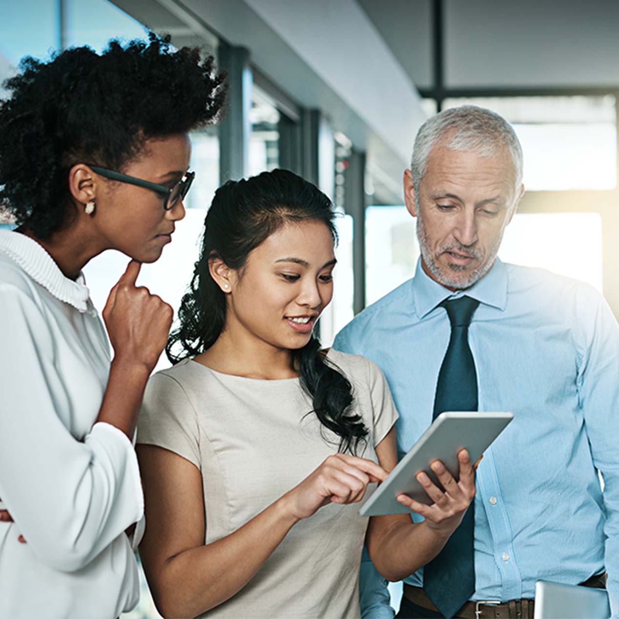 Two female and one male coworker standing together looking at data.