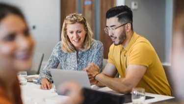 Photo of people looking at. laptop on a table. 