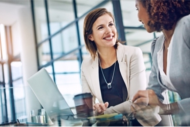 Two professional women sitting together and conversing in an office