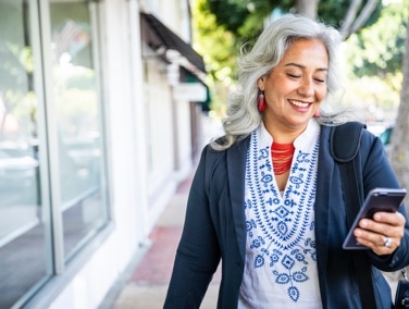 Person looking at mobile phone while walking outside.