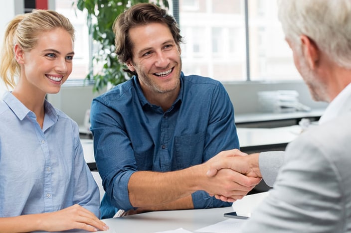 Man and woman shaking hands with a banker.