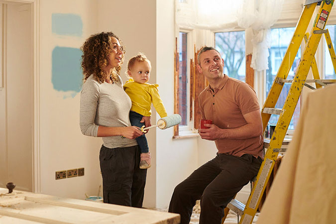 Couple with young child standing in newly painted room