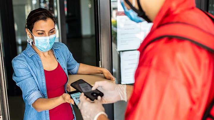 Woman who owns a restaurant accepting a payment from a customer using a mobile device.