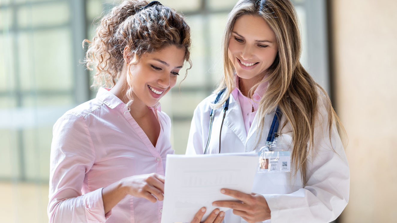 Two women looking at healthcare paperwork. One is a doctor and the other is a patient.