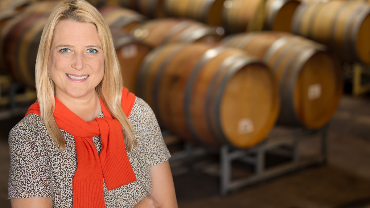 Alison Martin in front of a series of wine barrels