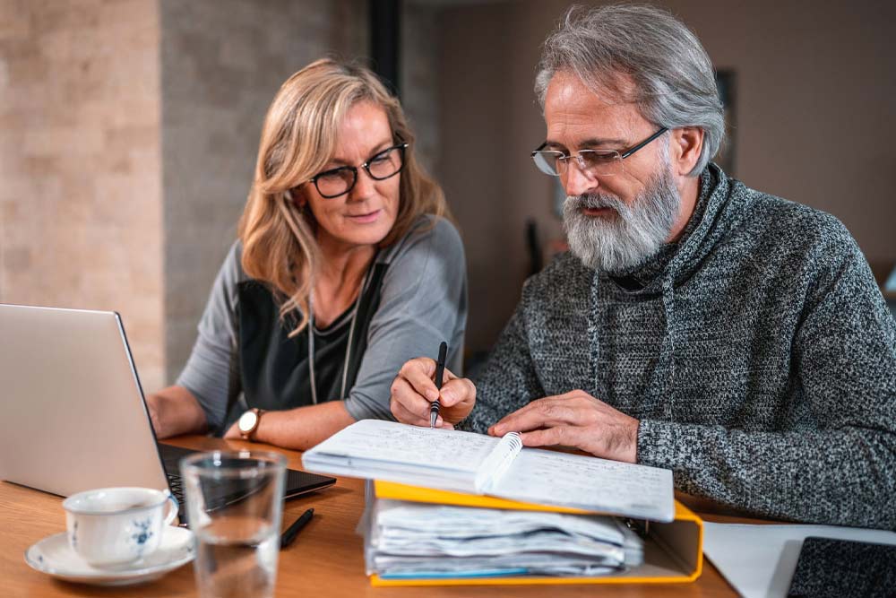 A man and woman in discussion facing a laptop