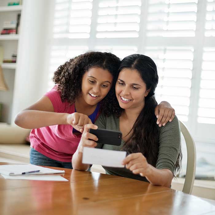 Imagen a colores de madre e hija mirando un cheque