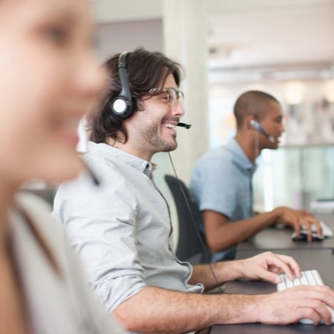 Three people sitting at desks with headsets on