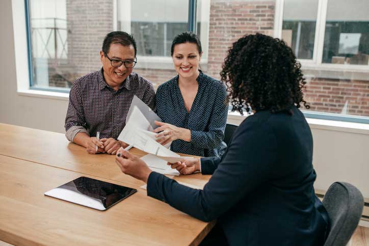 A banker going through paperwork with a happy couple.