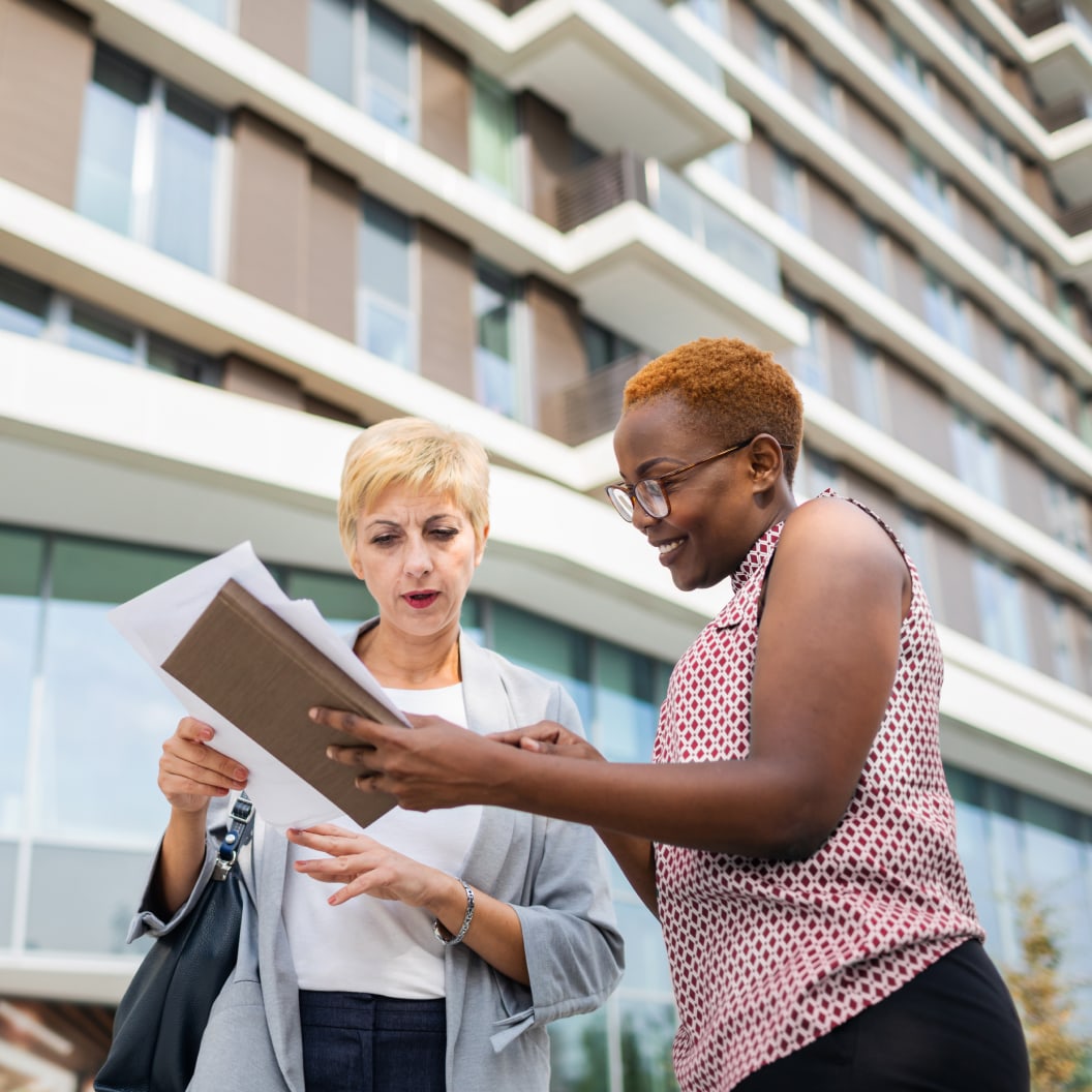 Two women standing next to each other looking at paperwork and checks and deciding how to handle them.